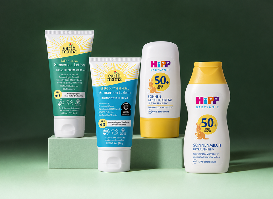 Earth Mama and HiPP sunscreen bottles on a green background