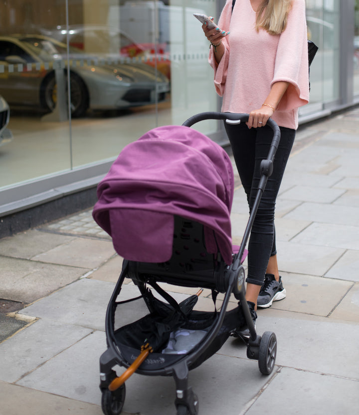 Mother pushing her European formula fed baby in a stroller.